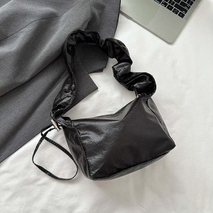 PU leather drawstring shoulder bag in black on a white surface.